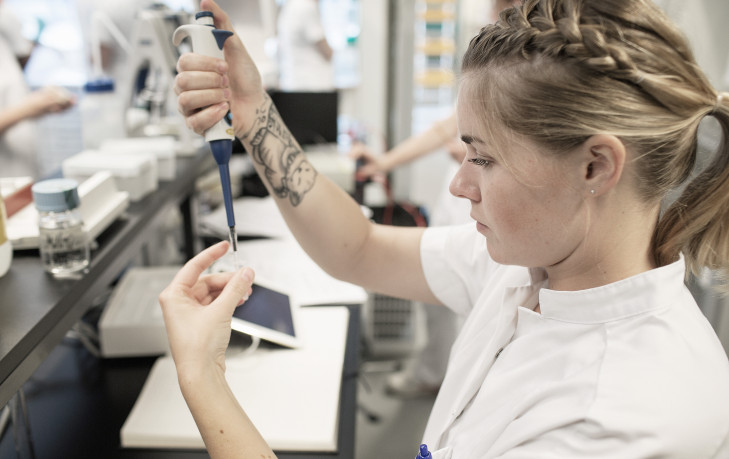 Studerende på laborantuddannelsen står med pipette