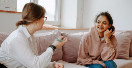 Studerende sidder i en sofa og smiler