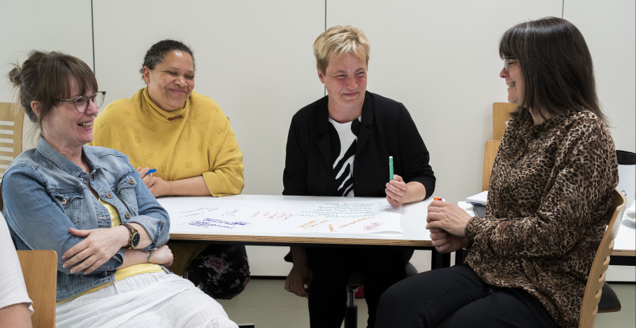 En gruppe studerende på meritpædagoguddannelsen arbejder i gruppe og griner sammen